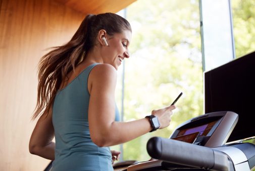 A woman listening to music while running on treadmill