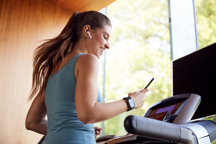A woman listening to music while running on treadmill
