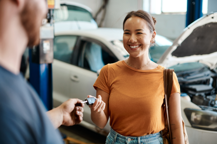 Woman getting her car key back from mechanics after servicing