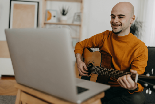 man learning guitar with computer
