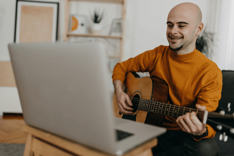 man learning guitar with computer