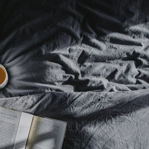 Cozy and comfy bed with a book and a cup of tea