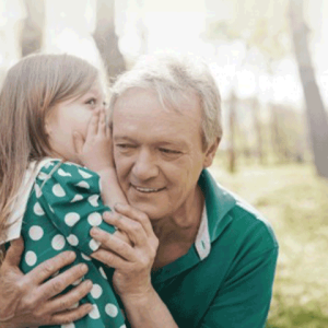 Audiology _tile A little girl murmuring in her grandpa's ear