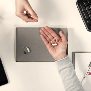An Amplifon employee giving hearing aids to a customer