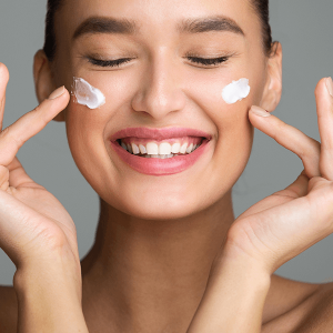 Woman applying cosmetic cream on her face