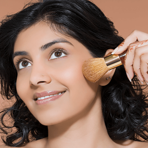 Woman with healthy skin applying cosmetic on her face